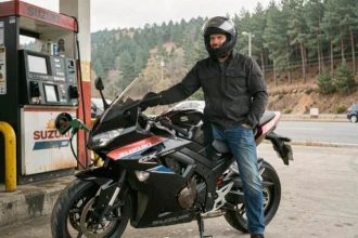 Motard faisant le plein de sa Suzuki GSX 750 dans une station-service rurale, illustrant la consommation réelle en usage mixte
